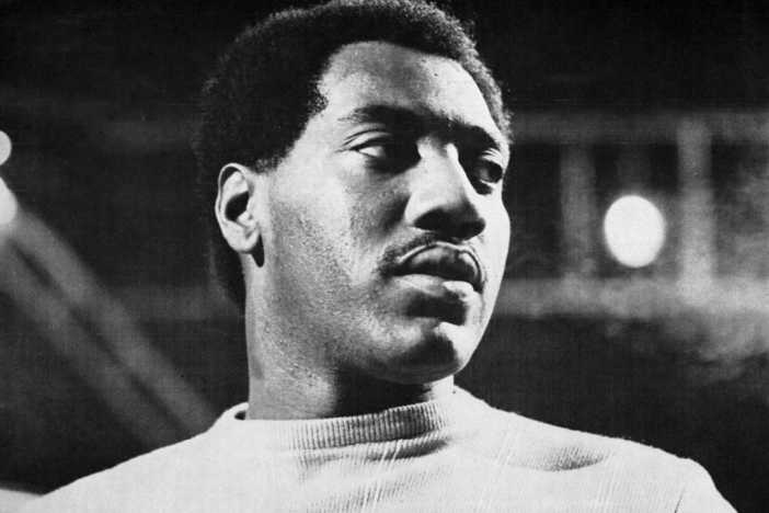 A black and white photo of Otis Redding, looking off-camera to the right, wearing a light sweater.