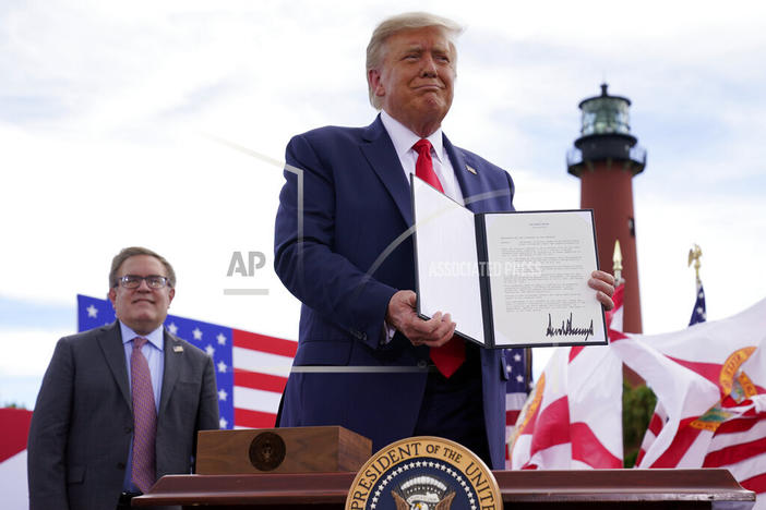 President Donald Trump holds a signed memorandum to expand the offshore drilling moratorium to Florida's Atlantic coast, Georgia and South Carolina after speaking at the Jupiter Inlet Lighthouse and Museum, Tuesday, Sept. 8, 2020, in Jupiter, Fla. At left is Environmental Protection Agency Administrator Andrew Wheeler.