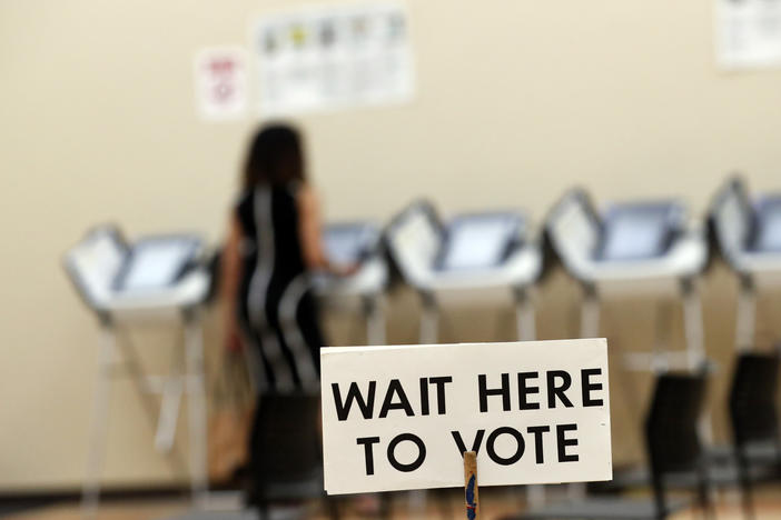 A sign tells voters to wait in line as they wait to vote.