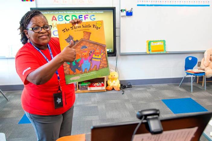 Teacher reading students a book virtually