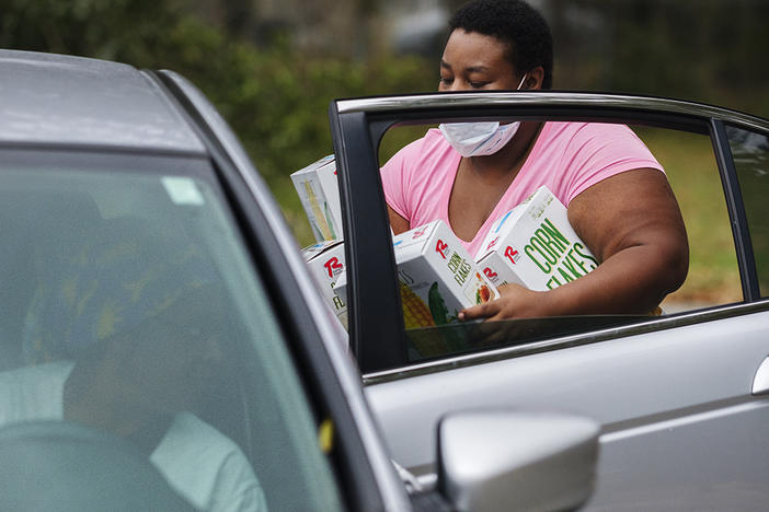 A member of Single Moms Connect lots groceries in the back of a recipient's car. According to the group Feeding American, just under half of the people accessing food aid during the COVID-19 recession are doing so for the first time in their lives. 