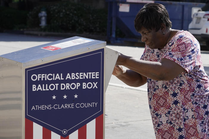 A voter drops their ballot off during early voting, Monday, Oct. 19, 2020, in Athens, Ga. With record turnout expected for this year's presidential election and fears about exposure to the coronavirus, election officials and advocacy groups have been encouraging people to vote early, either in person or by absentee ballot. (AP Photo/John Bazemore)