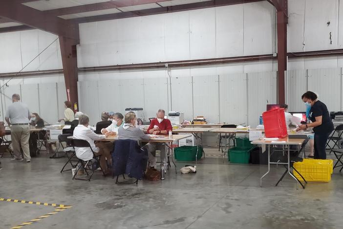 workers process absentee ballots in a warehouse