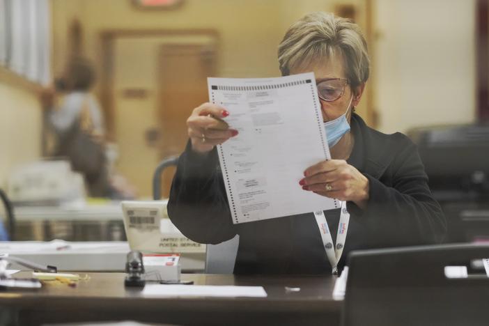 poll worker inspects absentee ballot