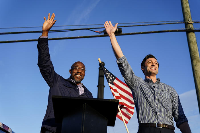 Georgia Democrats Raphael Warnock, left, and Jon Ossoff, right, gesture toward a crowd during a campaign rally in Marietta, Ga in November 2020. The two won seats to the U.S. Senate in runoff races in January 2021.