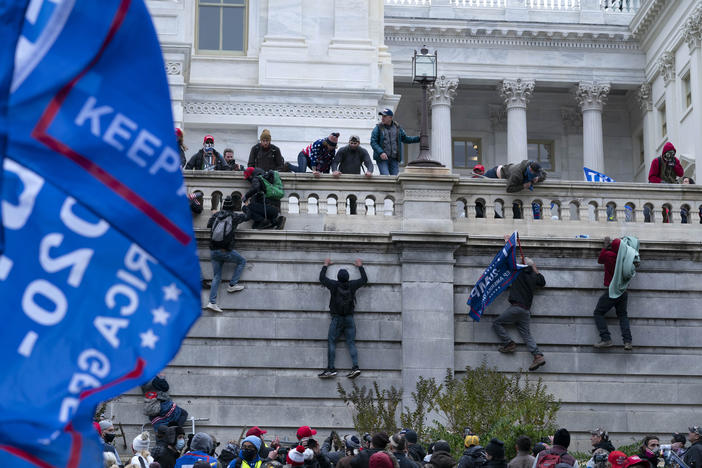 A mob scales a wall at the U.S. capitol.