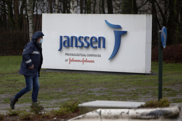 A man walks by a sign outside Johnson & Johnson subsidiary, Janssen Pharmaceutical, in Geel, Belgium, Wednesday, Feb. 3, 2021. 