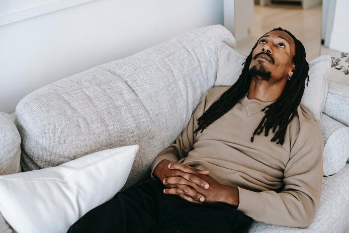 Pensive Black man lying on couch