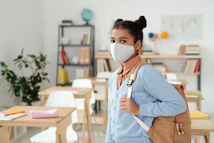 A girl with a backpack wearing a mask