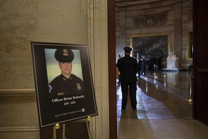  In this Feb. 2, 2021, file photo a placard is displayed with an image of the late U.S. Capitol Police officer Brian Sicknick on it as people wait for an urn with his cremated remains to be carried into the U.S. Capitol to lie in honor in the Capitol Rotunda in Washington.