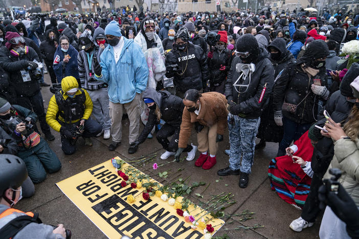 Flowers are placed on a banner as demonstrators gather outside the Brooklyn Center Police Department on Tuesday, April 13, 2021.