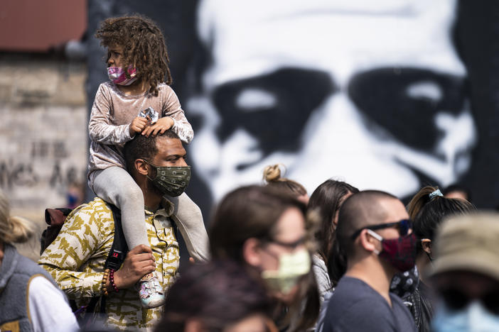 A mural of George Floyd looms behind a crowd of demonstrators gathered for a solidarity rally in memory of Floyd and Daunte Wright in Minneapolis.