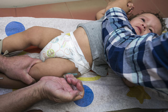 An infant receives a MMR vaccine in the leg.