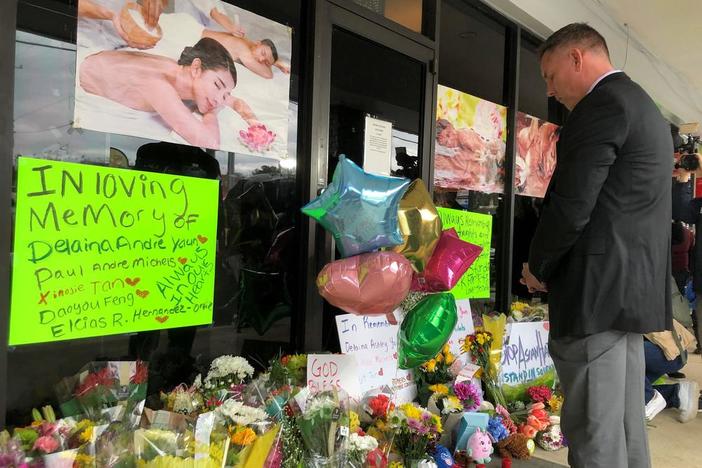 Cherokee County Sheriff Frank Reynolds bows his head after placing a bouquet of flowers outside Young's Asian Massage in Acworth, Ga., on Thursday, March 18, 2021.