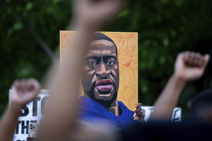 People march through the streets of Atlanta with a poster of George Floyd.