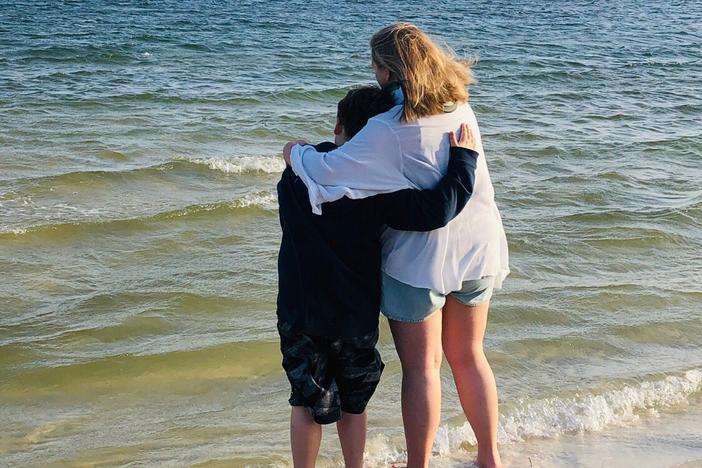 Brandon Little and his sister, Kylee, stand on a shore looking over waves.