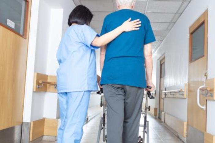 Nurse walking elderly person down hall