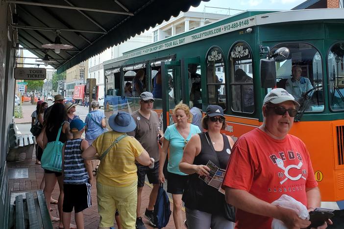 Tourists disembark from a tour trolley while others wait to board
