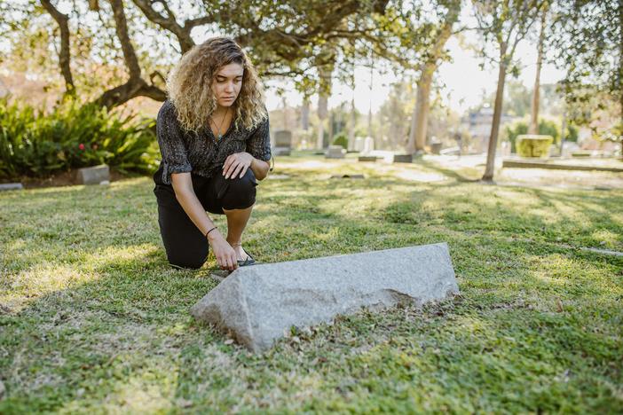 A woman kneels at a grave
