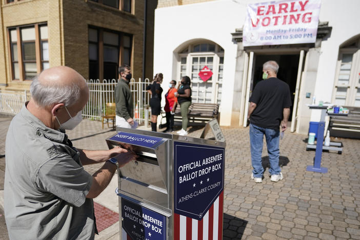 In this Monday, Oct. 19, 2020 file photo, a voter submits a ballot in an official drop box during early voting in Athens, Ga. Georgia’s secretary of state says, Tuesday, June 15, 2021, his office is reviewing the handling of paperwork related to ballot drop boxes in the state’s most populous county during last year’s election.