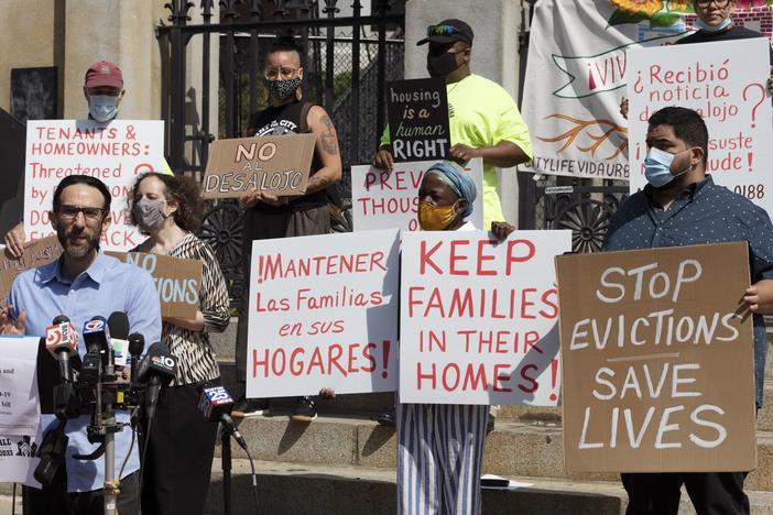 People from a coalition of housing justice groups hold signs protesting evictions during a news conference outside the Statehouse, Friday, July 30, 2021, in Boston.