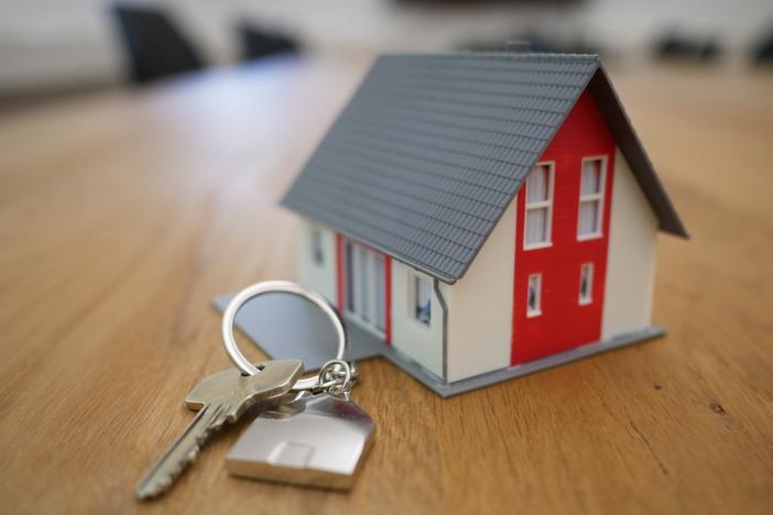 A photo of a house key next to a miniature house