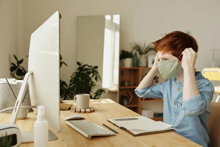 Kid wearing mask in front of computer