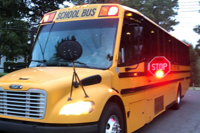 A school bus with its stop sign closing