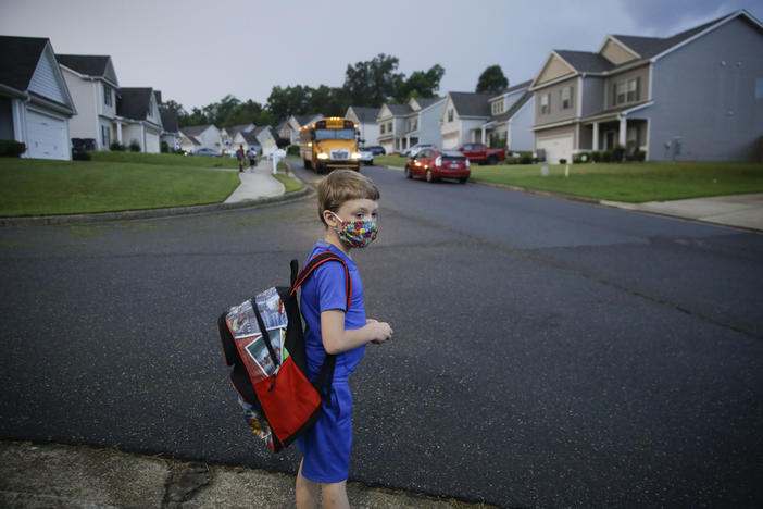 In this Aug. 3, 2020, file photo, Paul Adamus, 7, waits at the bus stop for the first day of 2020-2021 school year in Dallas, Ga. 