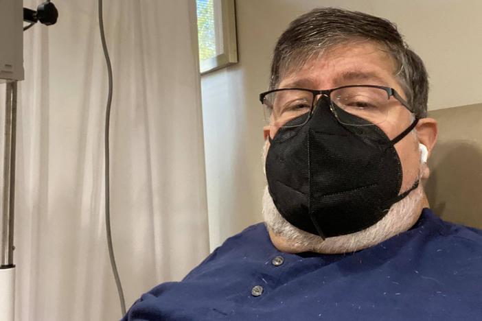 Dennis Loubiere in a black face mask while receiving an infusion of monoclonal antibodies