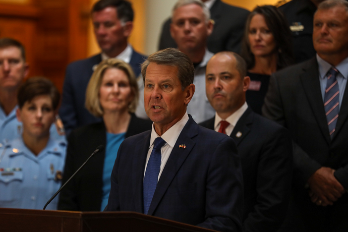 Gov. Brian Kemp surrounded by politicians and first responders