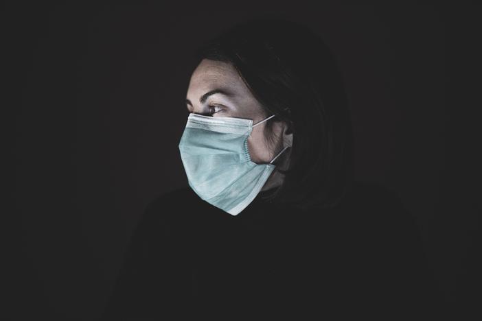 A person in a surgical mask looking to the right