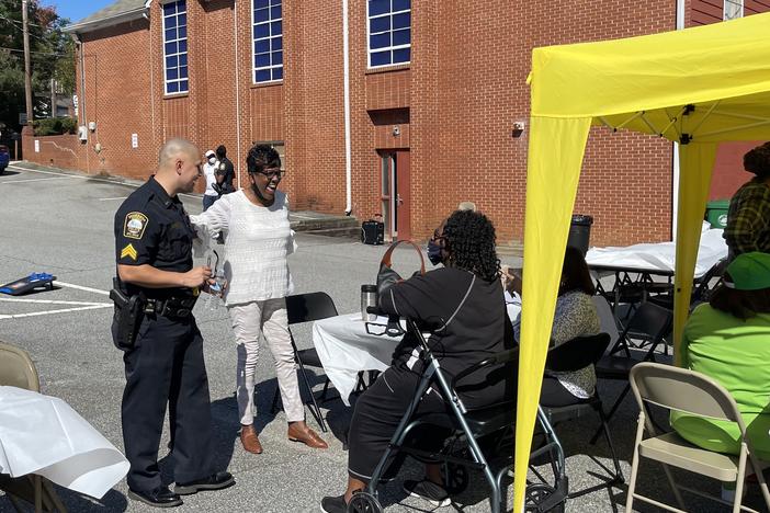 Community members and a police officer conversing at China Grove Baptist Church in Brookhaven.