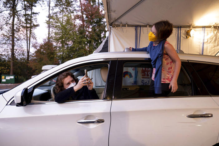 An excited Cate Zeigler-Amon, 10, hangs out of the car as she waits with her mom, Sara Zeigler, to receive her first dose of COVID-19 vaccine at the Viral Solutions vaccination and testing site in Decatur, Ga. on the first day COVID-19 vaccinations were available for children from 5 to 12 on Wednesday, Nov. 3, 2021. The pair arrived one and a half hours before the site opened to be first in line.