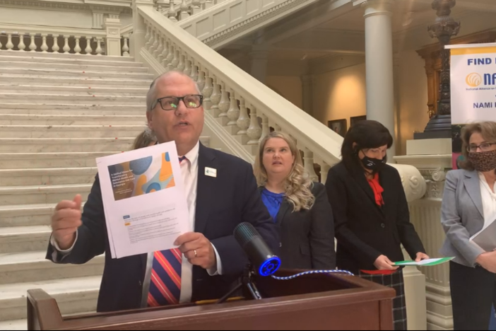 Jeff Breedlove holds a printed copy of the Georgia Mental Health Policy Partnership's Unified Vision for Transforming Mental Health and Substance Use Care in Georgia.