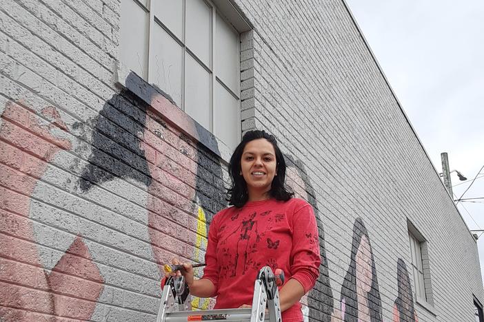 Mayelli Meza is painting a mural on a wall of the Oakwood Cafe in downtown Dalton.