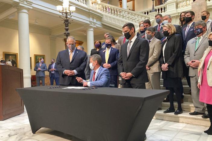 Georgia Gov. Brian Kemp, seated, hands a pen to Georgia House Speaker David Ralston on Monday, March 22, 2021, at the state capitol in Atlanta after signing a tax cut bill. Tax breaks for many Georgians, new requirements for physicians to be trained about avoiding sexual assault, and pay raises for some judges are among new legal provisions taking effect Saturday, Jan. 1, 2022 in Georgia.