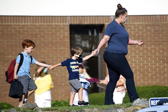 Kids are led to Blue Ridge Elementary School for the first day of classes in Evans, Ga., Monday morning, Aug. 3, 2020.
