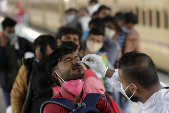 A health worker collects a swab sample from a traveler at a railway station to test for COVID-19, before he is allowed entry into the city, in Mumbai, India, Tuesday, Jan. 4, 2022. 
