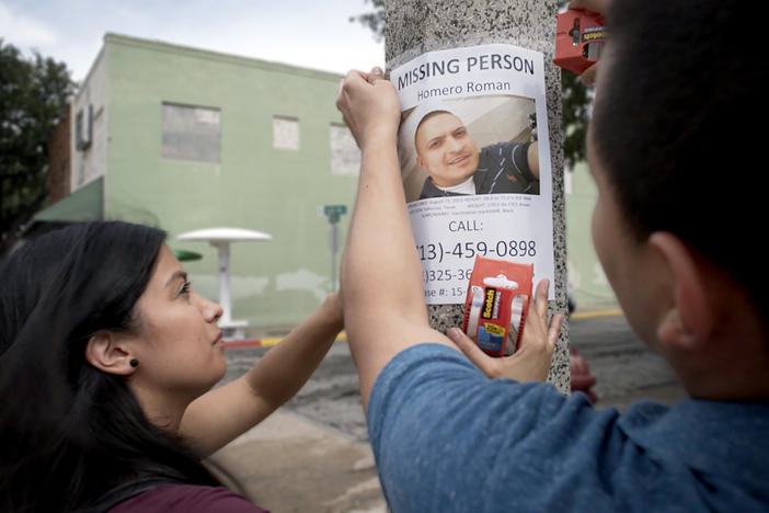 A man and woman put up a missing person poster.