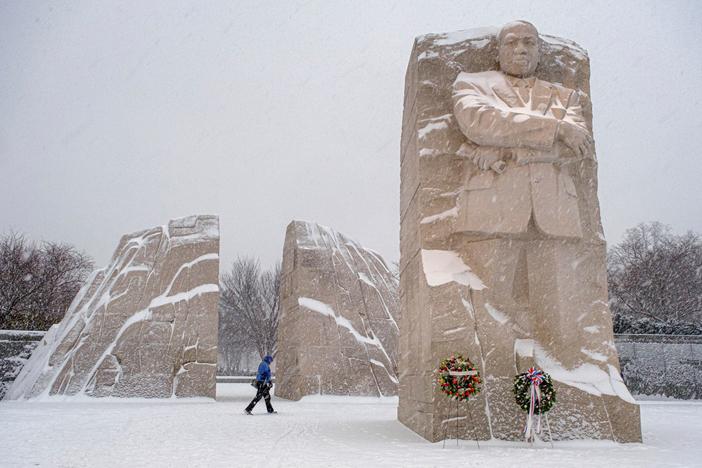 A visitor walks through the Martin Luther King, Jr. Memorial as a winter storm blows through the Washington area, Sunday, Jan. 16, 2022. Ceremonies scheduled for the site on Monday, to mark the Martin Luther King, Jr. national holiday have been canceled because of the weather.