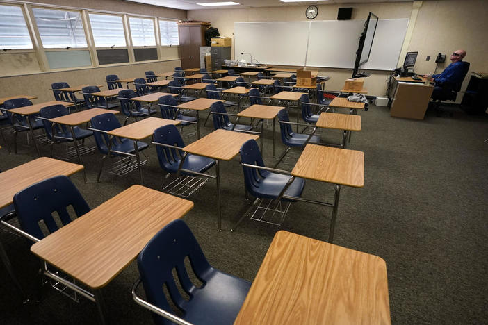 In this Aug. 18, 2020, file photo, math teacher Doug Walters sits among empty desks as he takes part in a video conference with other teachers to prepare for at-home learning at Twentynine Palms Junior High School in Twentynine Palms, Calif. California.