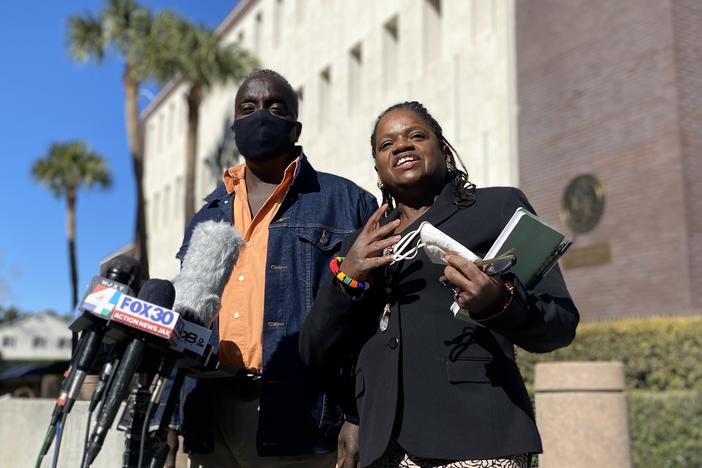 Ahmaud Arbery's father, Marcus Arbery, and civil rights lawyer Barbara Arnwhine address reporters outside the Brunswick federal courthouse on Feb. 14, 2022. Several news microphones are situated in front of them.