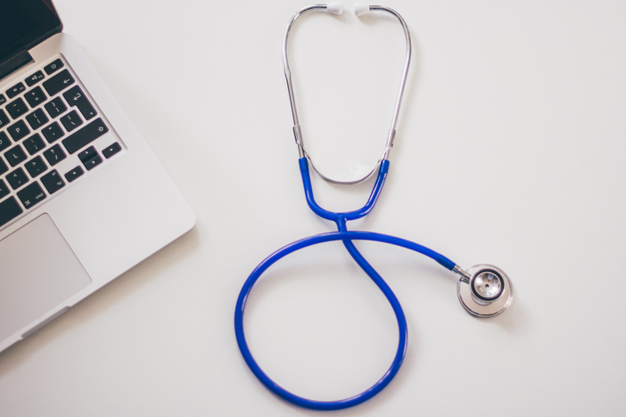 An image of a blue stethoscope and laptop computer