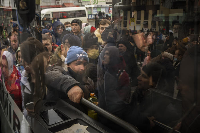 People try to get on a bus as they leave Kyiv, Ukraine, Thursday, Feb. 24, 2022. Russia launched a wide-ranging attack on Ukraine on Thursday, hitting cities and bases with airstrikes or shelling, as civilians piled into trains and cars to flee.