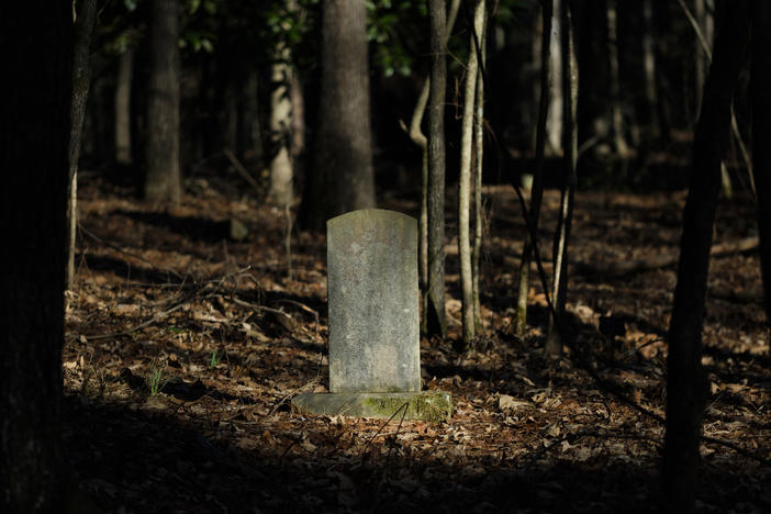 A grave marker amid the trees in the African American cemetery outside the Penfield Cemetery of Mercer University.