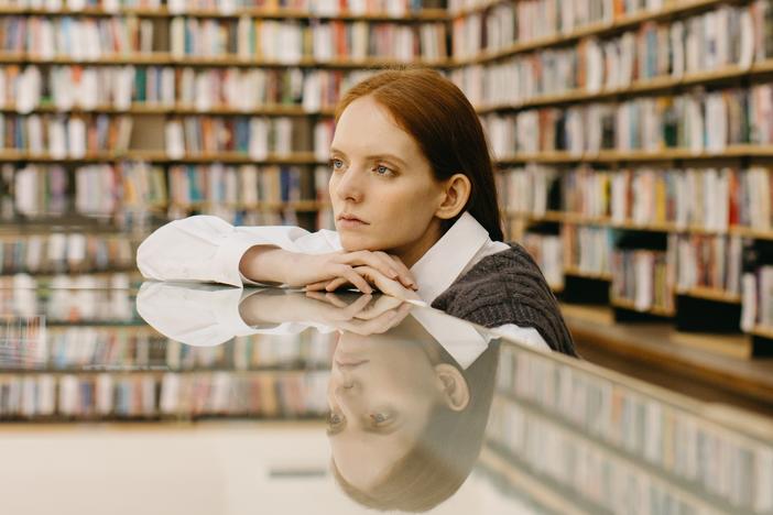 A woman sits at a table in a library