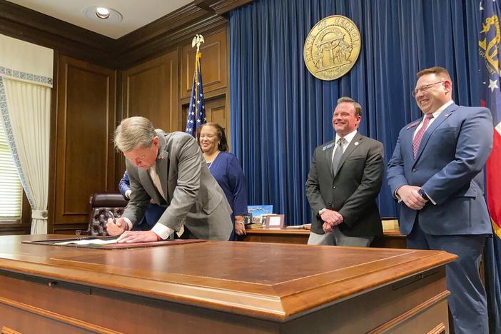 Georgia Gov. Brian Kemp signs a bill to give state income refunds of more than $1.1 billion on Wednesday, March 23, 2022, at the Georgia capitol in Atlanta. The measure gives refunds of $250 to $500 to people who filed tax returns for 2020 and 2021. 