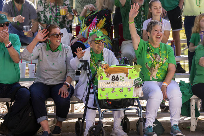 Mimi Rissman, 85, center, holds a sign announcing her 86th birthday while watching the St. Patrick's Day parade, Thursday, March 17, 2022, in historic downtown Savannah, Ga. After nearly two centuries, the Irish holiday has become Savannah's most profitable tourist draw and street party for hundreds of thousands of locals and visitors.