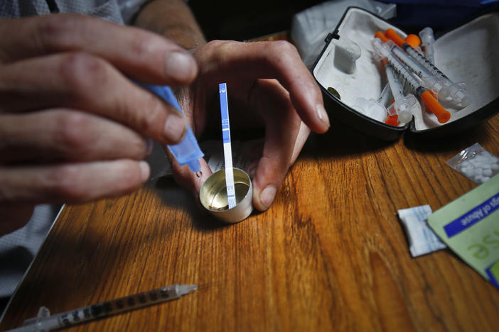 A person prepares heroin, placing a fentanyl test strip into the mixing container to check for contamination.